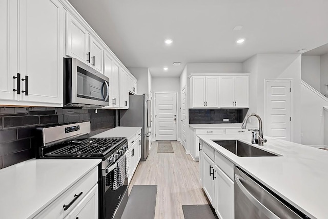 8522 Leroi Dr, Austin, TX 78744 - kitchen featuring stainless steel appliances, a sink, light countertops, white cabinetry, and recessed lighting
