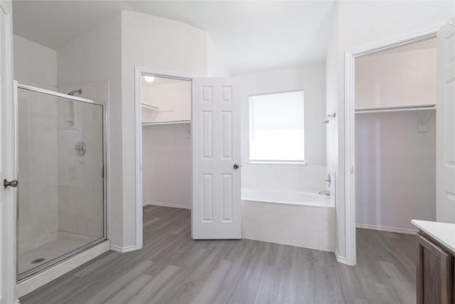 15406 Ecorio Dr, Austin, TX 78728 - bathroom with a bath, a walk in closet, a stall shower, wood finished floors, and vanity