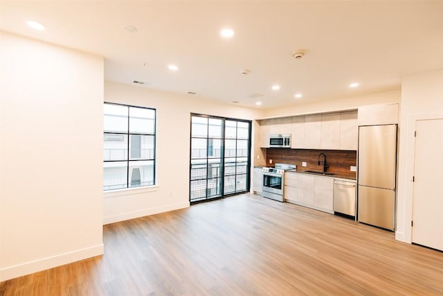 4315 S Congress Ave Unit 520, Austin, TX 78745 - kitchen with tasteful backsplash, modern cabinets, stainless steel appliances, light wood finished floors, and a sink