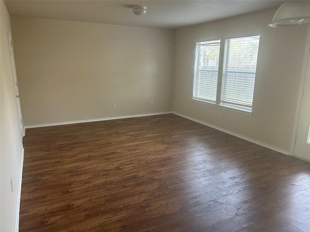 unfurnished room with dark wood-type flooring and baseboards