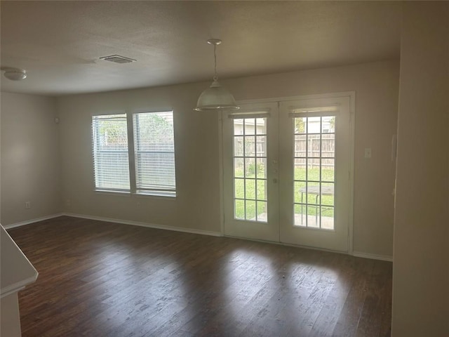 spare room with a healthy amount of sunlight, baseboards, and dark wood finished floors