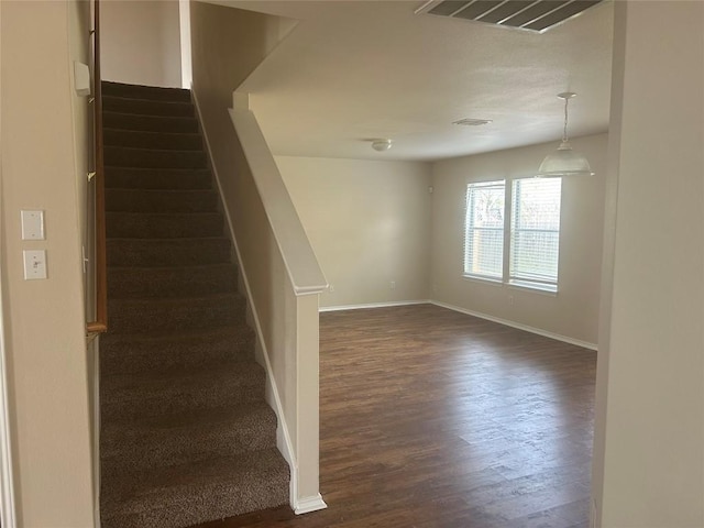stairway with wood finished floors, baseboards, and visible vents