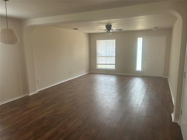 spare room with arched walkways, dark wood-style flooring, baseboards, and a ceiling fan