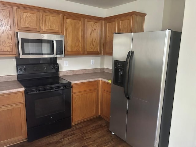 kitchen featuring light countertops, brown cabinetry, dark wood-style floors, and stainless steel appliances