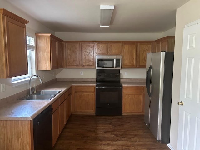 kitchen featuring dark wood-type flooring, brown cabinetry, black appliances, a sink, and light countertops
