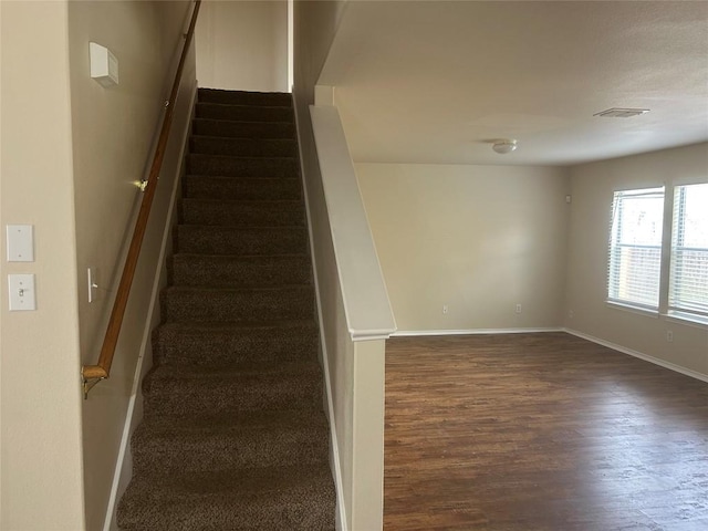 stairs with visible vents, baseboards, and wood finished floors