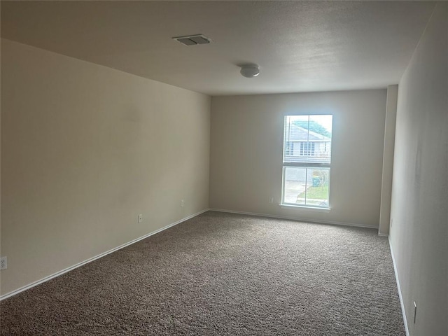 unfurnished room featuring carpet, visible vents, and baseboards