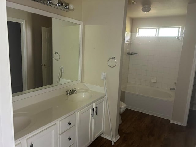 bathroom featuring double vanity,  shower combination, toilet, a sink, and wood finished floors