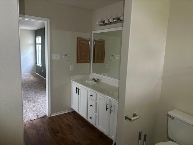 bathroom with toilet, wood finished floors, vanity, and baseboards