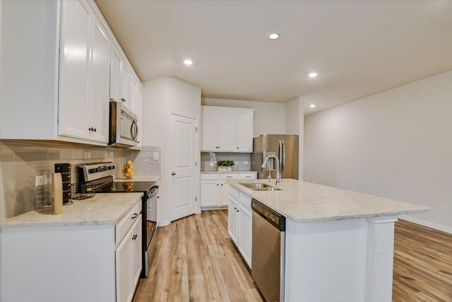 105 Saviano Rd, Hutto, TX 78634 - kitchen with stainless steel appliances, light wood finished floors, tasteful backsplash, a sink, and an island with sink