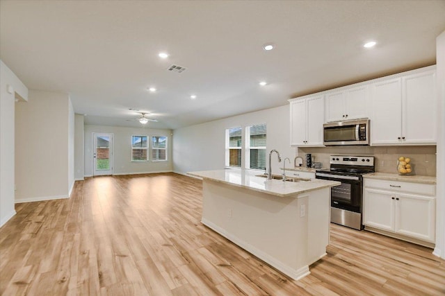 105 Saviano Rd, Hutto, TX 78634 - kitchen featuring stainless steel appliances, a sink, a ceiling fan, open floor plan, and white cabinets