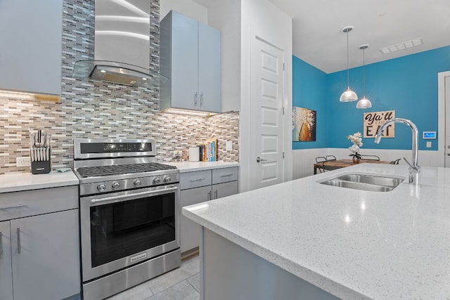 8922 Menchaca Rd Unit 204, Austin, TX 78748 - kitchen with stainless steel gas range, a sink, wall chimney range hood, decorative light fixtures, and light stone counters