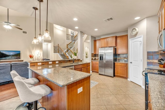 18003 Linkhill Dr, Dripping Springs, TX 78620 - kitchen with stainless steel appliances, open floor plan, a sink, ceiling fan, and brown cabinetry