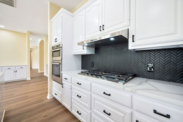 8316 Talbot Ln, Austin, TX 78746 - kitchen featuring under cabinet range hood, stainless steel appliances, backsplash, white cabinetry, and recessed lighting