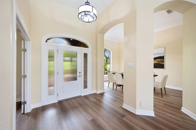 8316 Talbot Ln, Austin, TX 78746 - foyer entrance featuring arched walkways, dark wood finished floors, baseboards, and crown molding