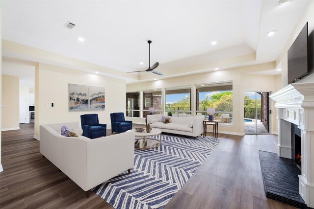 8316 Talbot Ln, Austin, TX 78746 - living room with a ceiling fan, a lit fireplace, wood finished floors, recessed lighting, and a tray ceiling