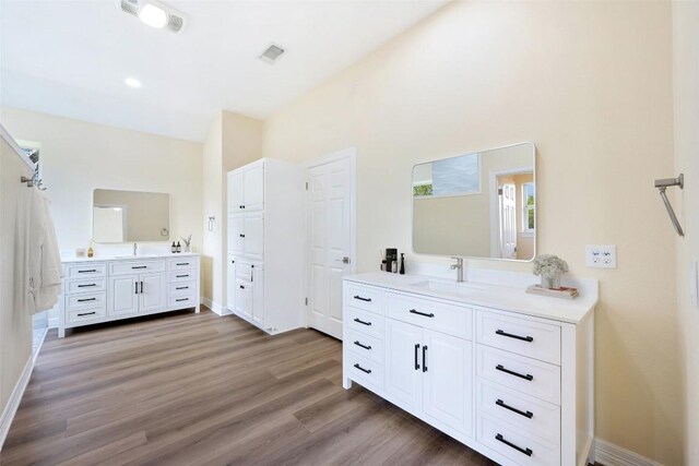 8316 Talbot Ln, Austin, TX 78746 - bathroom featuring two vanities, wood finished floors, and baseboards