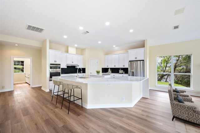 8316 Talbot Ln, Austin, TX 78746 - kitchen featuring appliances with stainless steel finishes, a large island, white cabinets, tasteful backsplash, and a sink
