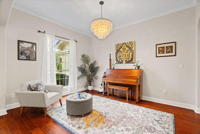 living area with a notable chandelier, baseboards, crown molding, and wood finished floors