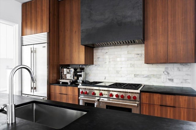 kitchen with premium appliances, a sink, modern cabinets, and premium range hood