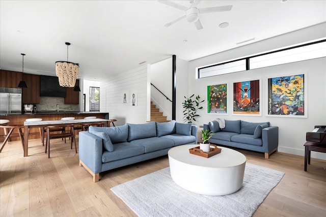 living room with visible vents, baseboards, ceiling fan, stairs, and light wood-style flooring