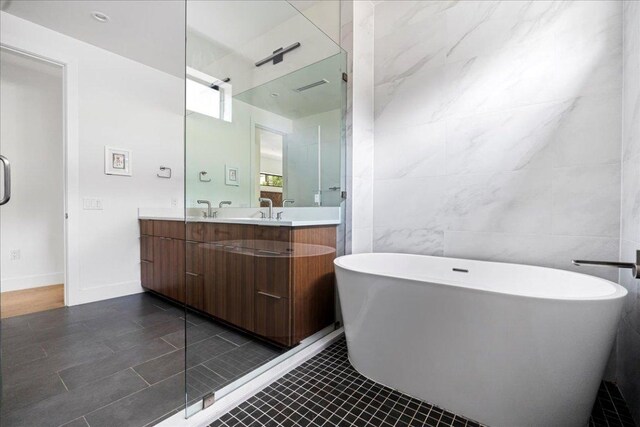 full bath featuring visible vents, a freestanding tub, tile walls, double vanity, and tile patterned floors