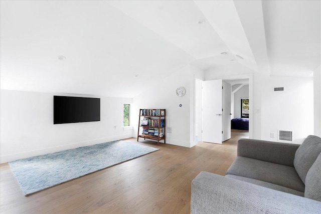 living area featuring baseboards, visible vents, light wood-type flooring, and vaulted ceiling