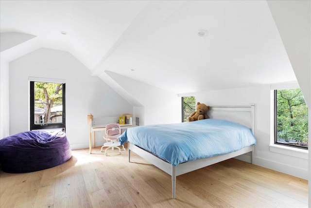 bedroom featuring baseboards, wood finished floors, and vaulted ceiling