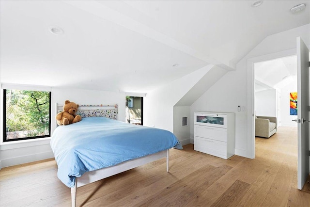 bedroom with light wood-style flooring, visible vents, baseboards, and lofted ceiling
