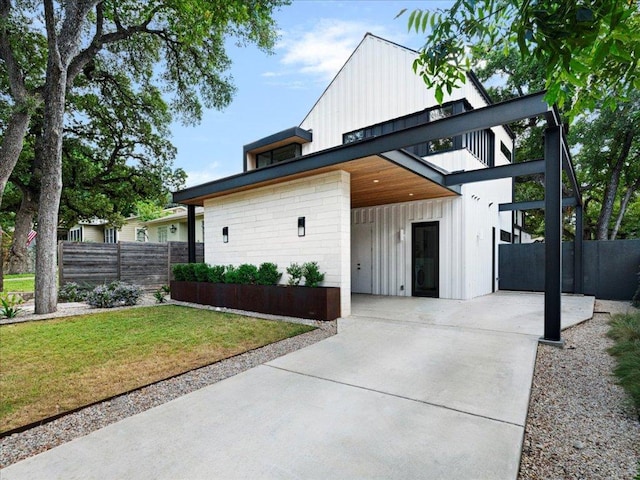 view of front of property featuring board and batten siding, a front yard, fence, and concrete block siding