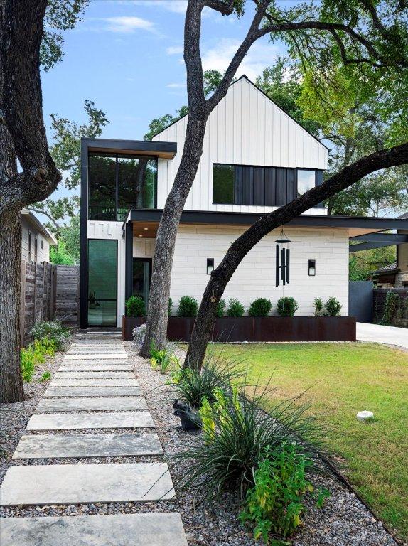 rear view of property with board and batten siding, fence, and a yard