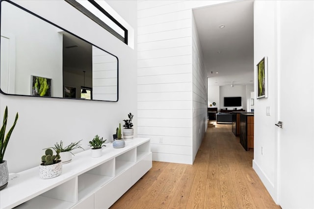 corridor featuring wooden walls and light wood-style floors