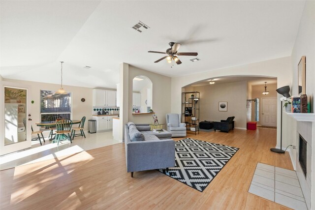 5216 Trading Bnd, Austin, TX 78735 - living room with arched walkways, light wood finished floors, ceiling fan, and a fireplace with flush hearth