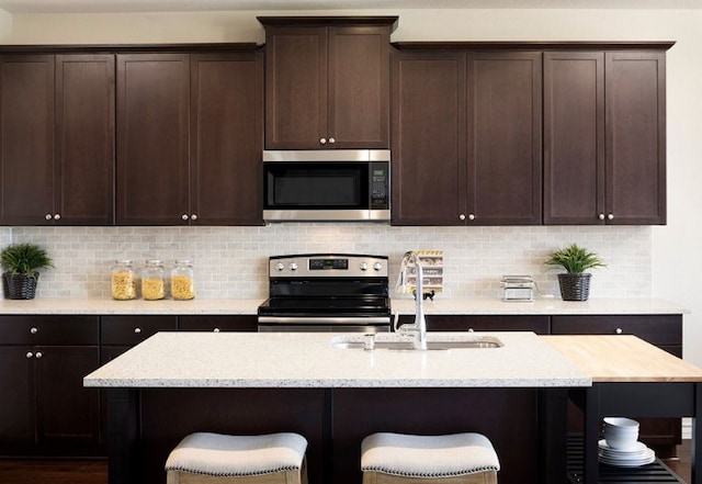 1517 Purple Martin Dr, Pflugerville, TX 78660 - kitchen with a kitchen bar, a sink, dark brown cabinets, and appliances with stainless steel finishes