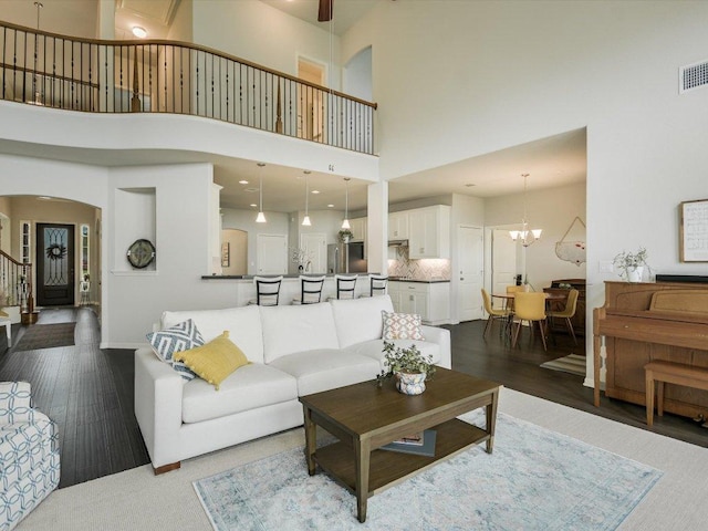 2733 Painted Sky Bnd, Leander, TX 78641 - living room with arched walkways, a high ceiling, dark wood-type flooring, stairway, and a chandelier