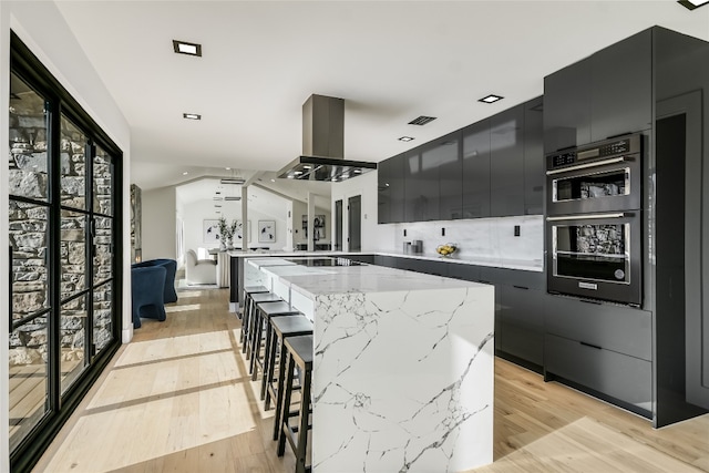 1903 Toro Canyon Rd, Austin, TX 78746 - kitchen with dark cabinetry, island range hood, light wood-style flooring, modern cabinets, and a kitchen island