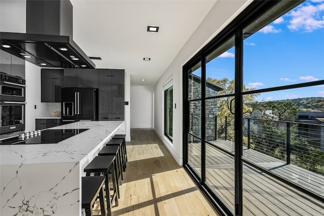 1903 Toro Canyon Rd, Austin, TX 78746 - kitchen featuring dark cabinetry, black appliances, island range hood, modern cabinets, and wood finished floors