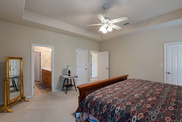 21507 Lakefront Dr, Lago Vista, TX 78645 - bedroom with light colored carpet, a raised ceiling, baseboards, connected bathroom, and ceiling fan