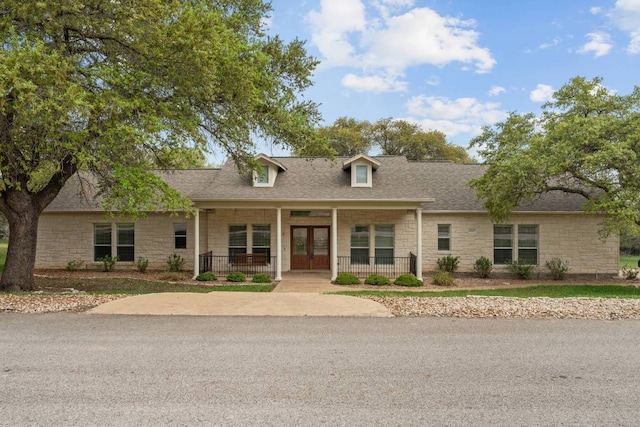 21507 Lakefront Dr, Lago Vista, TX 78645 - cape cod home with stone siding, french doors, a porch, and a shingled roof