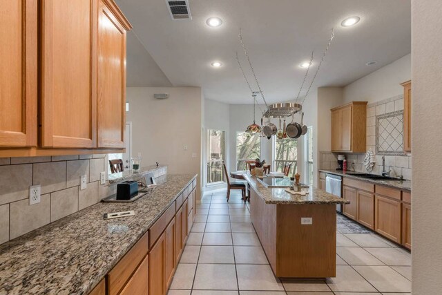 21507 Lakefront Dr, Lago Vista, TX 78645 - kitchen with backsplash, a sink, an island with sink, light stone countertops, and recessed lighting