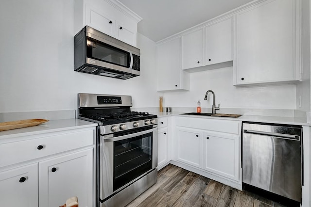 5313 Martin Ave, Austin, TX 78751 - kitchen with stainless steel appliances, a sink, white cabinets, wood finished floors, and light countertops