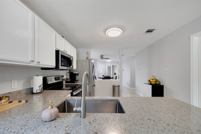 12404 Granton Cv, Austin, TX 78754 - kitchen with a sink, stainless steel appliances, white cabinetry, light stone countertops, and visible vents
