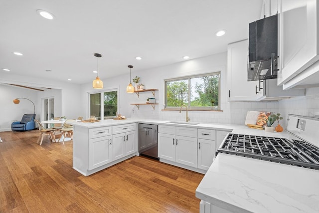 kitchen featuring stainless steel dishwasher, gas range, a sink, a peninsula, and light wood-type flooring