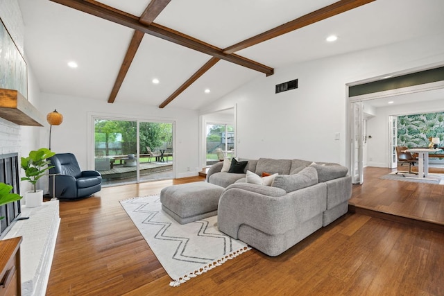 living room with wood finished floors, a brick fireplace, and recessed lighting
