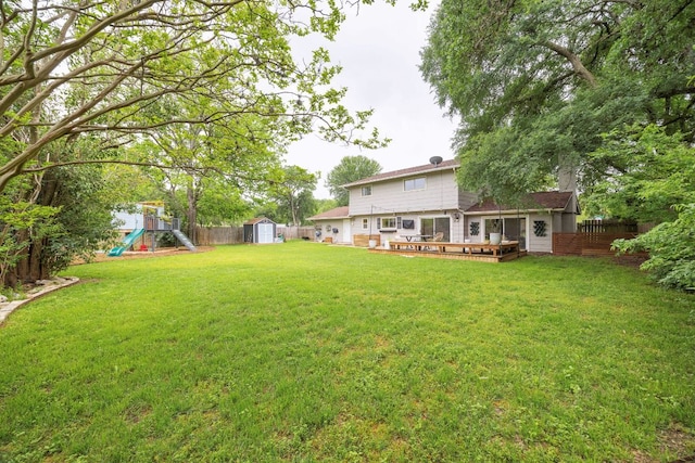 view of yard featuring a shed, a playground, an outbuilding, and a deck