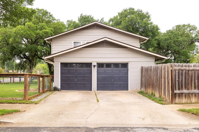 garage featuring driveway and fence