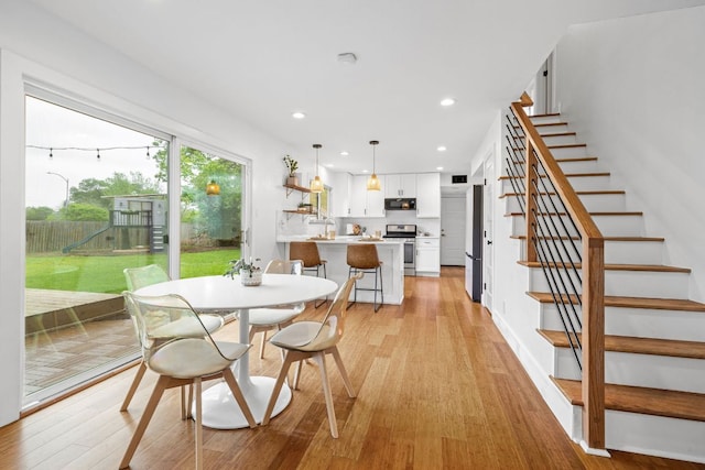dining room with light wood finished floors, stairs, and recessed lighting