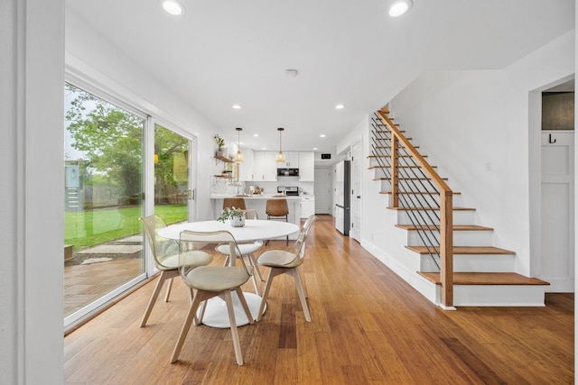dining room with light wood-style flooring, stairs, recessed lighting, and baseboards