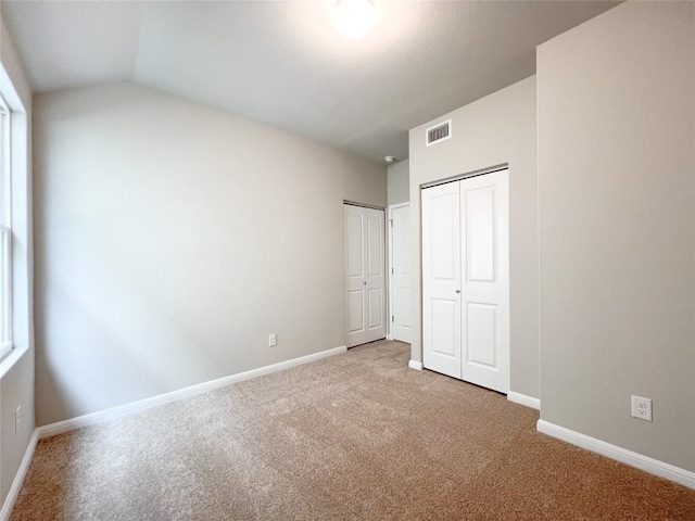676 Ferrule Dr, Kyle, TX 78640 - unfurnished bedroom with carpet floors, multiple closets, baseboards, and lofted ceiling