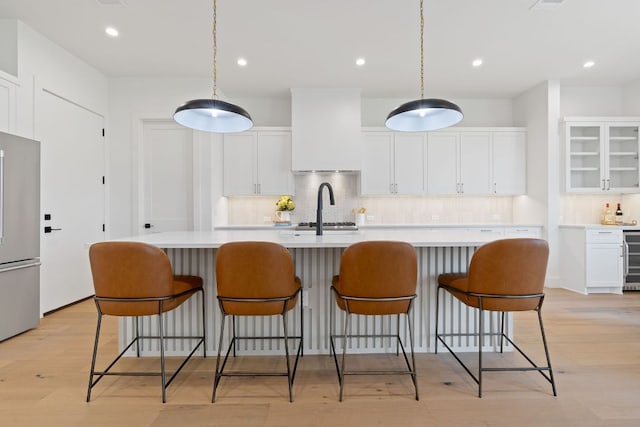 814 Stark St, Austin, TX 78756 - kitchen featuring stainless steel fridge, decorative backsplash, light countertops, white cabinets, and an island with sink